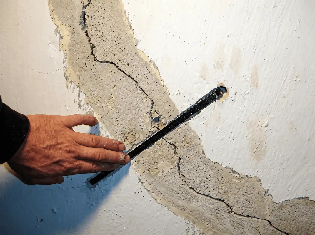 A wall with a large crack is being inspected by a professional in Fort Worth, TX